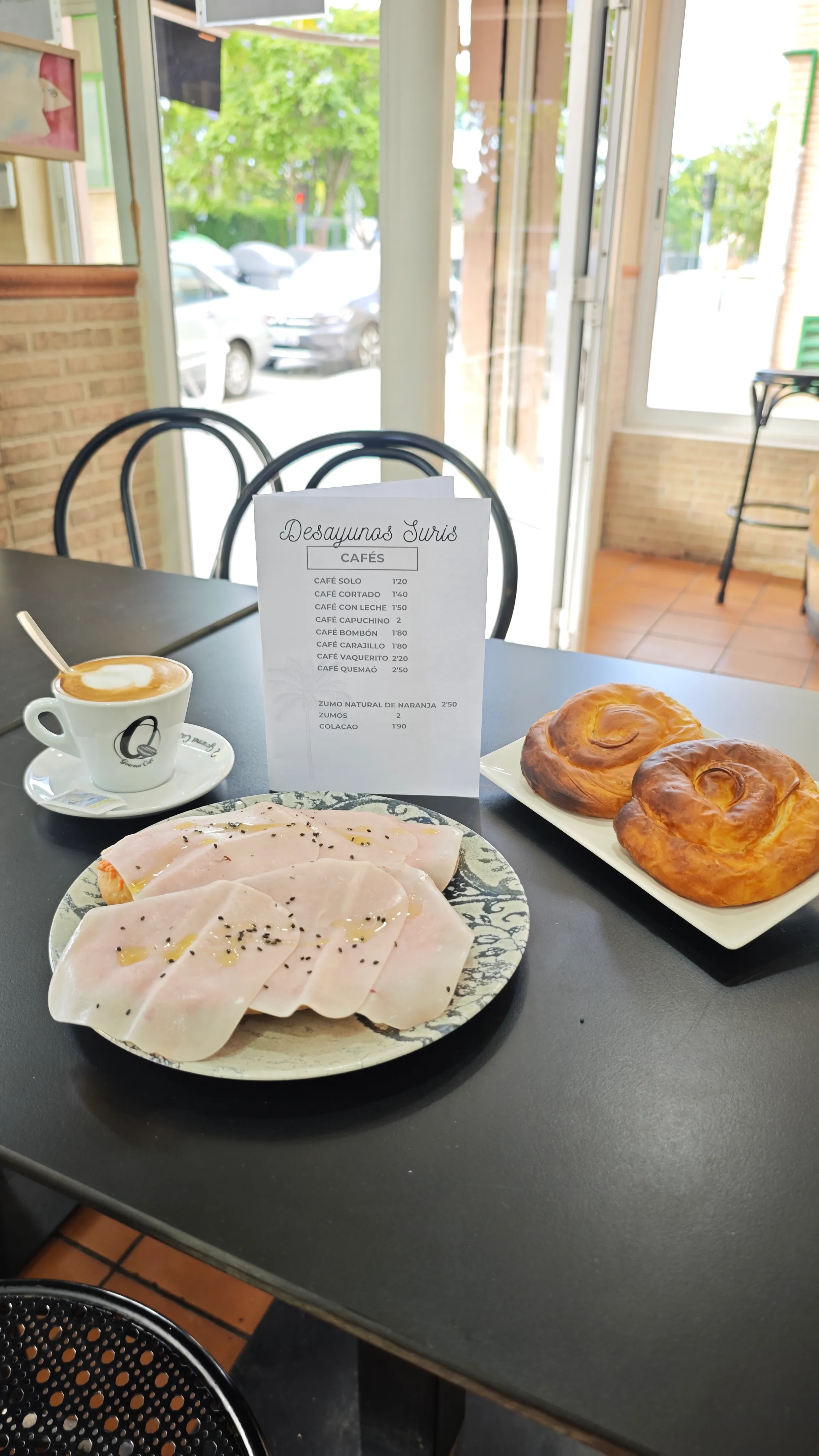 Desayuno con café con leche, tostada con jamón york, dos caracolas y la carta de cafés